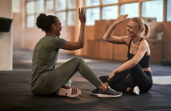 Laughing women high-fiving together after a workout